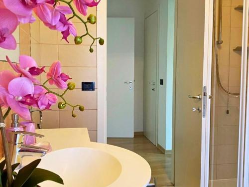 baño con lavabo y flores rosas en la pared en La Perla Nel Borgo, en Cappella Maggiore