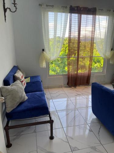 a living room with a blue couch and a window at THOMAS BOND APARTAMENTOS in Santa Bárbara de Samaná