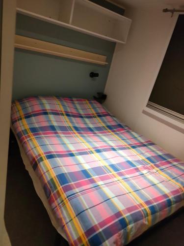 a bed in a room with a plaid blanket at Lieu de paix in Camiers