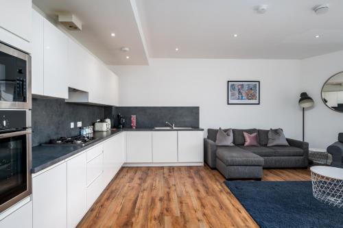 a kitchen and living room with white cabinets and a couch at Casa Fresa - Cowgate House in Dundee