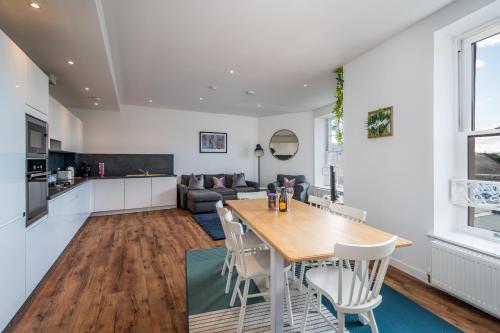 a kitchen and living room with a wooden table and chairs at Casa Fresa - Cowgate House in Dundee