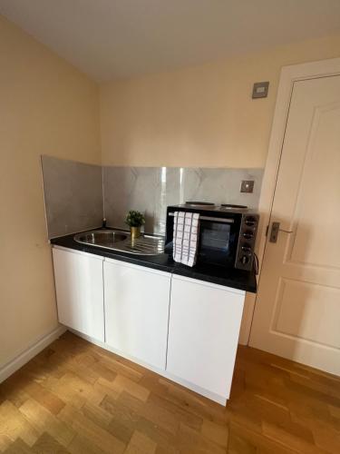 eine Küche mit Mikrowelle und Spüle in der Unterkunft Stunning House 15 min from Wembley arena in London