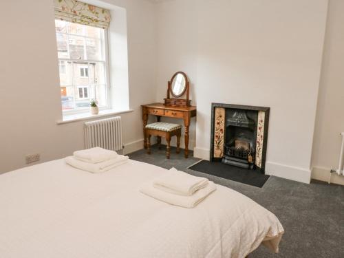 a white bedroom with a bed and a fireplace at Bay Tree Cottage in Richmond