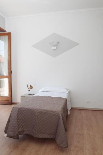 a white bedroom with a bed and a wooden floor at La Porta del Sole in Caselle Torinese