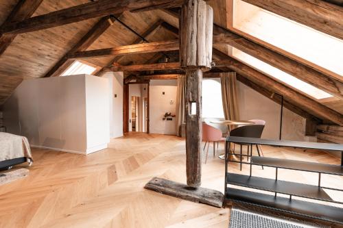 a loft with wooden ceilings and a table and chairs at H5 Grauer Bär Studios & More in Innsbruck