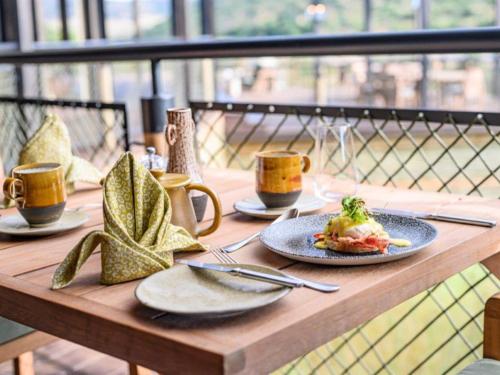 un tavolo in legno con piatti di cibo e tazze di caffè di Madwaleni River Lodge - Babanango Game Reserve a Ulundi