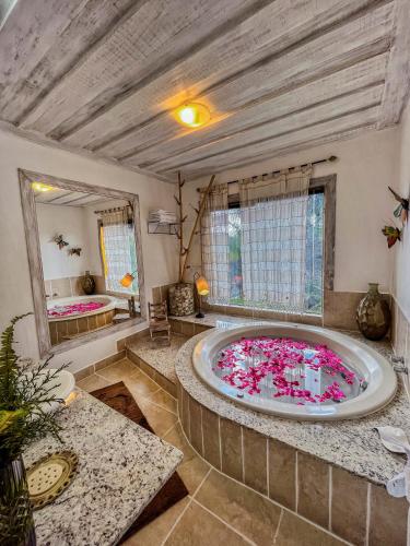 a large bathroom with a large tub filled with pink flowers at Pousada Villa 3 Lagos in Santo Antônio do Pinhal