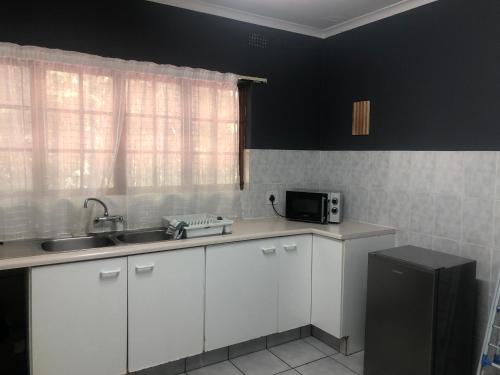 a kitchen with white cabinets and a sink and a microwave at Hillcrest/Waterfall Garden Hideaway! in Waterfall