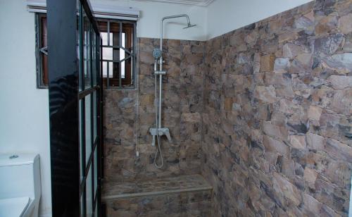 a stone walled shower with a shower head in a bathroom at Sosa Guest House in Sekondi-Takoradi