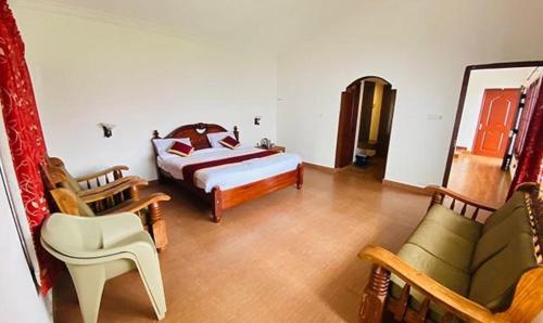- une chambre avec un lit et des chaises dans l'établissement FabHotel Blossom Cottages, à Kodaikānāl