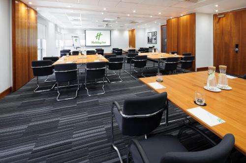 a conference room with tables and chairs and a projection screen at Holiday Inn Reading South M4 Jct 11 by IHG in Reading
