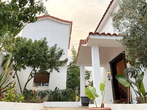 une maison blanche avec des arbres devant elle dans l'établissement Tranquila Vista - Villa au cœur de la nature, à Tanger