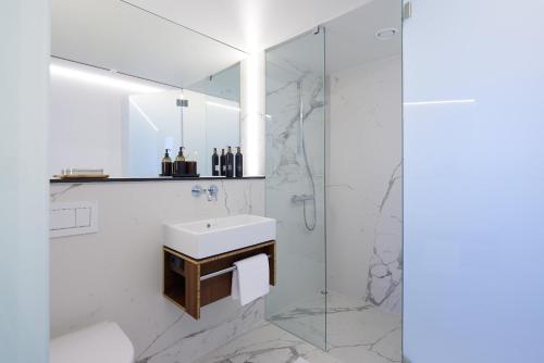 een witte badkamer met een wastafel en een douche bij TIN INN l Hückelhoven einfach gut - Das Hotel aus hochwertig ausgebauten Überseecontainern in Hückelhoven