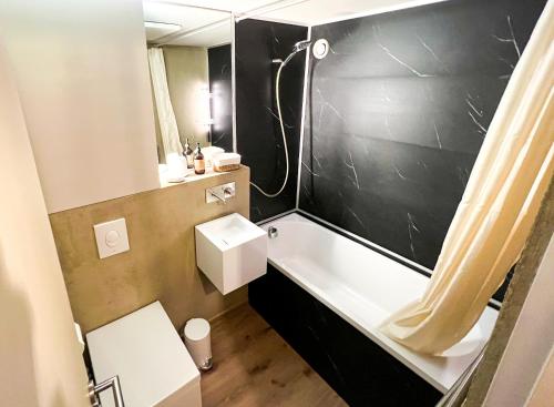 uma casa de banho com uma banheira branca e uma parede preta em Le Little Fox - IMMODREAMS - Avoriaz em Avoriaz