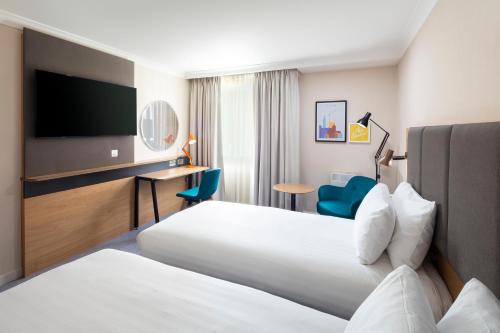 a hotel room with two beds and a flat screen tv at Holiday Inn Reading South M4 Jct 11 by IHG in Reading