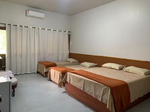 a bedroom with two beds and a window with curtains at Pousada Rural Estação Verde in Bonito