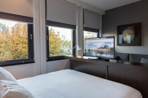 Schlafzimmer mit einem Bett, einem TV und Fenstern in der Unterkunft B-aparthotel Kennedy in Den Haag