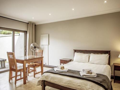 a bedroom with a bed and a table and a desk at Two Oceans Stay in Cape Town