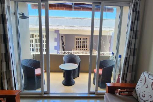 a room with a balcony with chairs and a table at Number 8, 2nd Floor, Pebble Bay Apartments in Grand Baie