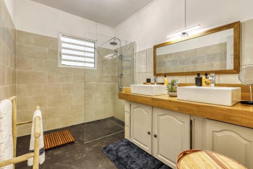 a bathroom with two sinks and a shower at Kaz Voyageur in Saint-Paul