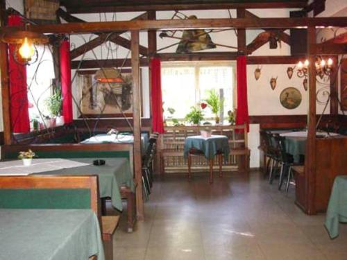 ein Restaurant mit Tischen, Stühlen und roten Vorhängen in der Unterkunft Gasthaus-Pension Zum Brandweiher in Amorbach