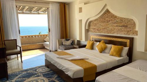 1 dormitorio con 2 camas y balcón con vistas al océano en Lux Suites Eden Seafront Apartments, en Shanzu