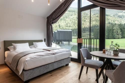 a bedroom with a bed and a table and a large window at Såndgøld Alpine Glamping in Campo Tures