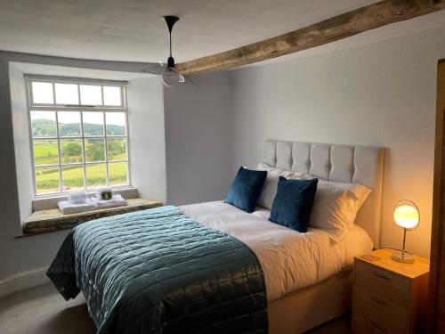 a bedroom with a bed with blue pillows and a window at Greenbank Farm House in Cartmel
