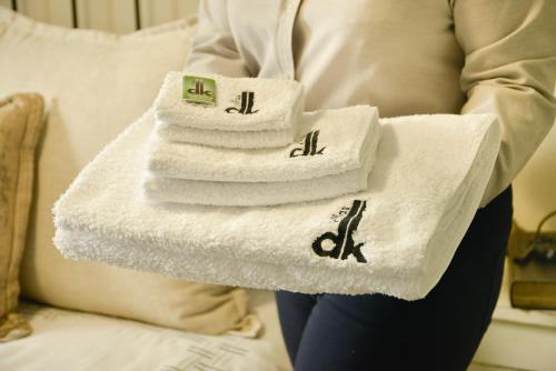 a woman holding a stack of towels on a bed at dk villas 4 Riverview, Hout Bay in Hout Bay