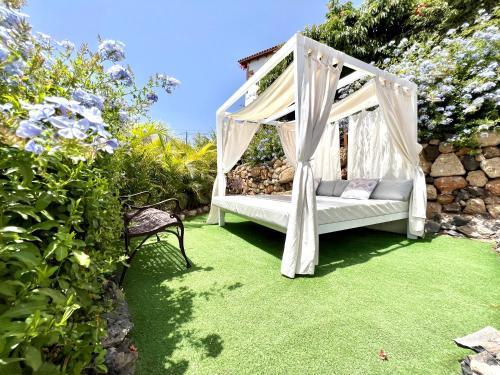 Wonderful Villa with heated infinity pool, Ocean View in Tenerife South في سان ميغيل ذي أبونا: أرجوحة في حديقة بها عشب أخضر وورود
