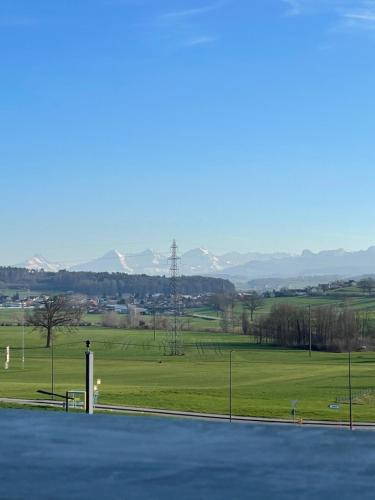 a tennis court with a field and mountains in the background at Mountain view apartment in Cressier near Murten 