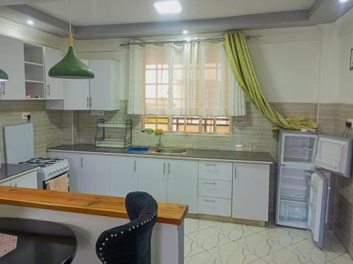 a kitchen with white cabinets and a sink and a window at Chloe One Bedroom in Nanyuki