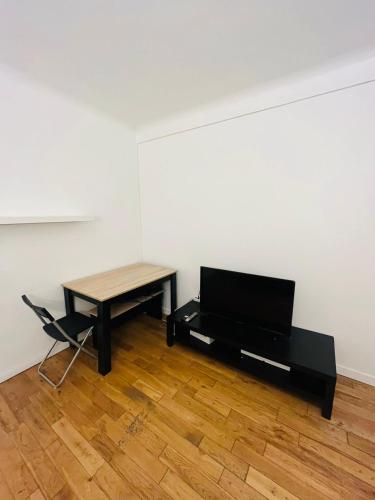 Cette chambre comprend un bureau, une table et une télévision. dans l'établissement Stationnement Gratuit, 3mn du Métro, Parfait pour Télétravailler, à Maisons-Alfort