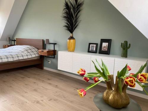 1 dormitorio con 1 cama y 1 mesa con flores en Penthouse with a view, en Breukelen
