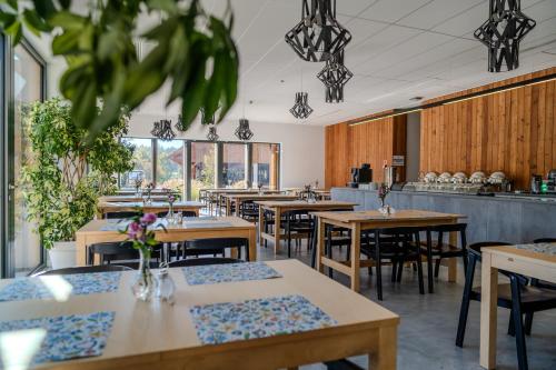 um restaurante com mesas e cadeiras de madeira e janelas em Hotel Skansen Conference&Spa em Studzieniec