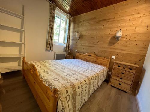une chambre avec un lit et un mur en bois dans l'établissement Chalet confort à Pra Loup, 4 pers, proche piste, balcon, animaux admis - FR-1-165A-61, à Uvernet