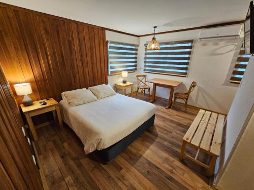 a bedroom with a bed and a table and a bench at Casa Ellies Hotel Boutique in Puerto Varas