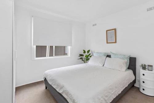 een witte slaapkamer met een bed en een raam bij Great Ocean Road Sandy Villa in Apollo Bay