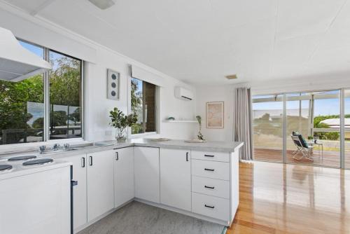 een keuken met witte kasten en grote ramen bij Great Ocean Road Sandy Villa in Apollo Bay