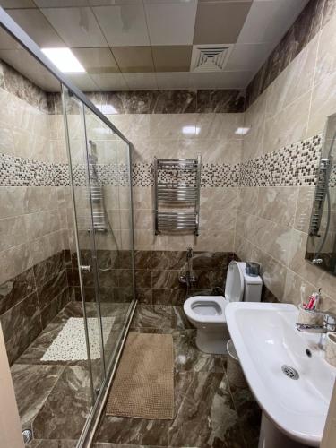 a bathroom with a shower and a toilet and a sink at Cozy & Spacious Apartment in Baku