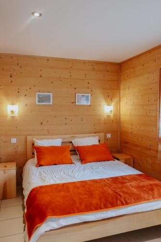 - une chambre avec un grand lit et des murs en bois dans l'établissement Chalet Les Hellebores, à La Toussuire