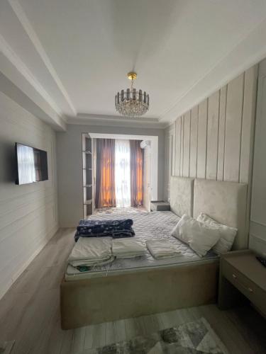 a bedroom with a large bed and a chandelier at Puli Sangin apartments in Dushanbe