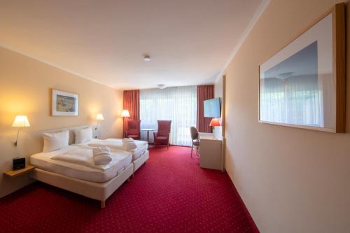 ノルダーナイにあるMichels Hanseatic Hotel Norderneyの赤いカーペットのベッドが備わるホテルルームです。