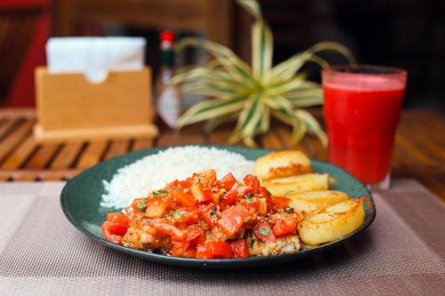 a green plate of food with rice and a drink at Pousada Porto Mare in Maresias