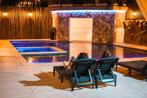 a woman laying in chairs in front of a swimming pool at Pousada Porto Mare in Maresias