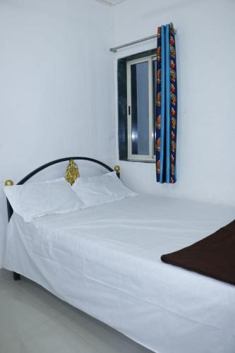 un letto bianco in una stanza con finestra di Omkar Holiday Home Revdanda a Revadanda