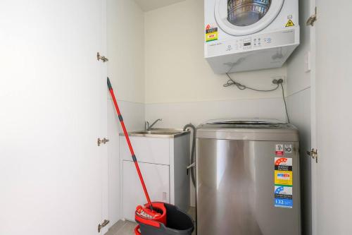 a red mop in a kitchen with a washing machine at Lidcombe 2Br Apt Near Olympic Park Train Shopping Center in Sydney
