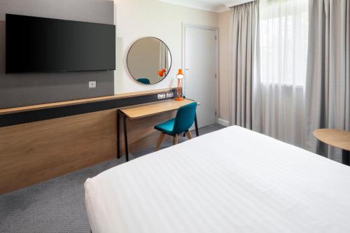 a hotel room with a bed and a desk and a mirror at Holiday Inn Reading South M4 Jct 11 by IHG in Reading