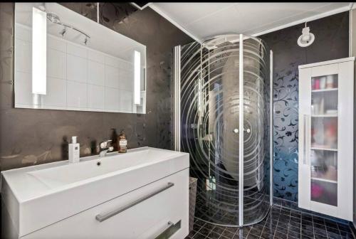 a bathroom with a sink and a glass shower at Rolig og avslappende in Tromsø