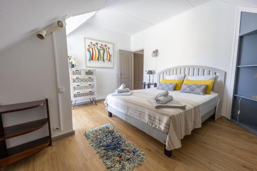 ein Schlafzimmer mit einem großen weißen Bett mit gelben Kissen in der Unterkunft Rooftop - magnifique penthouse proche du lagon de l Hermitage-Les-Bains in L'Ermitage-Les-Bains